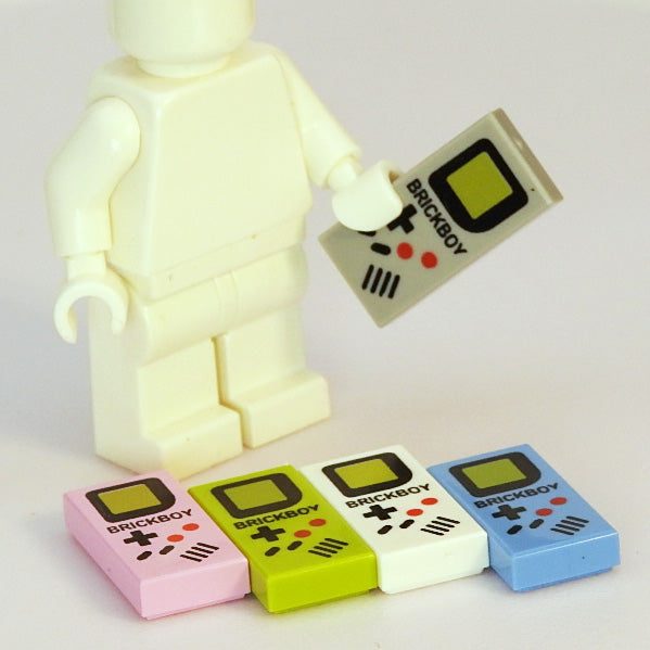 Toy figure holding a remote control with 'BRICKBOY' branding, surrounded by colorful 'BRICKBOY' products on a light background.
